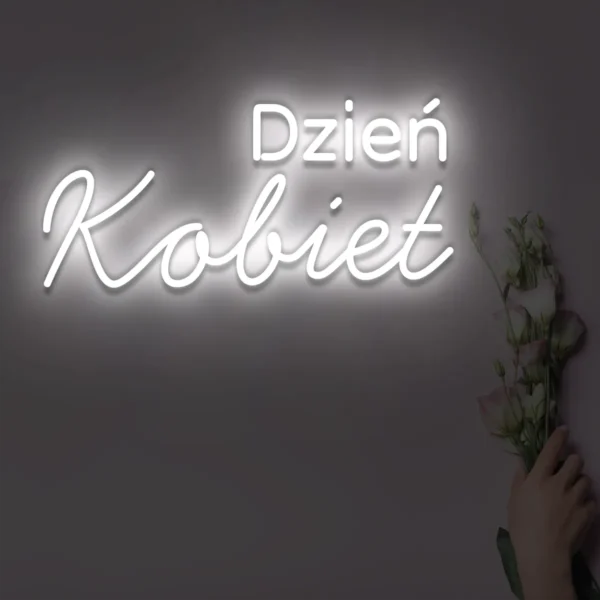 Biały neon LED z napisem Dzień Kobiet na ścianie, obok kwiaty