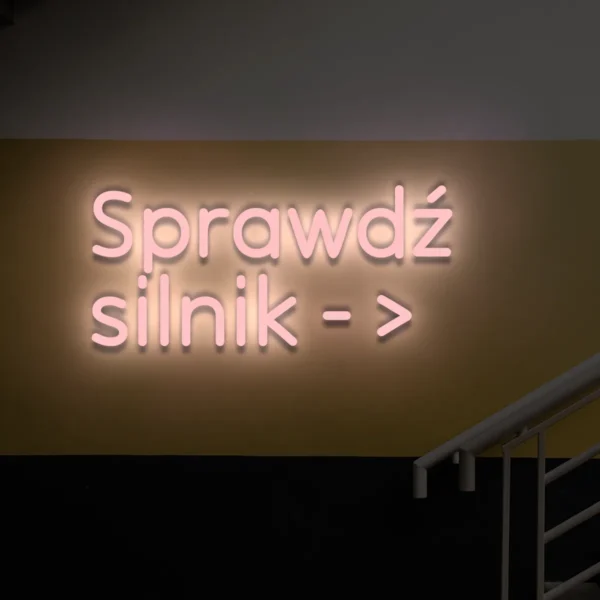 Jasnoróżowy neon z napisem „Sprawdź silnik →” dekoracja wskazująca