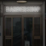 Biały neon LED z napisem BARBERSHOP nad wejściem