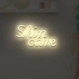 Neonowy napis Skin care w kolorze beżowym dekoracja ścienna
