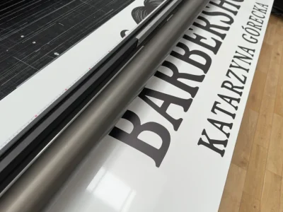 Reklamowy szyld dla barbershopu z czarnym napisem, drukowany na Dibondzie metodą UV